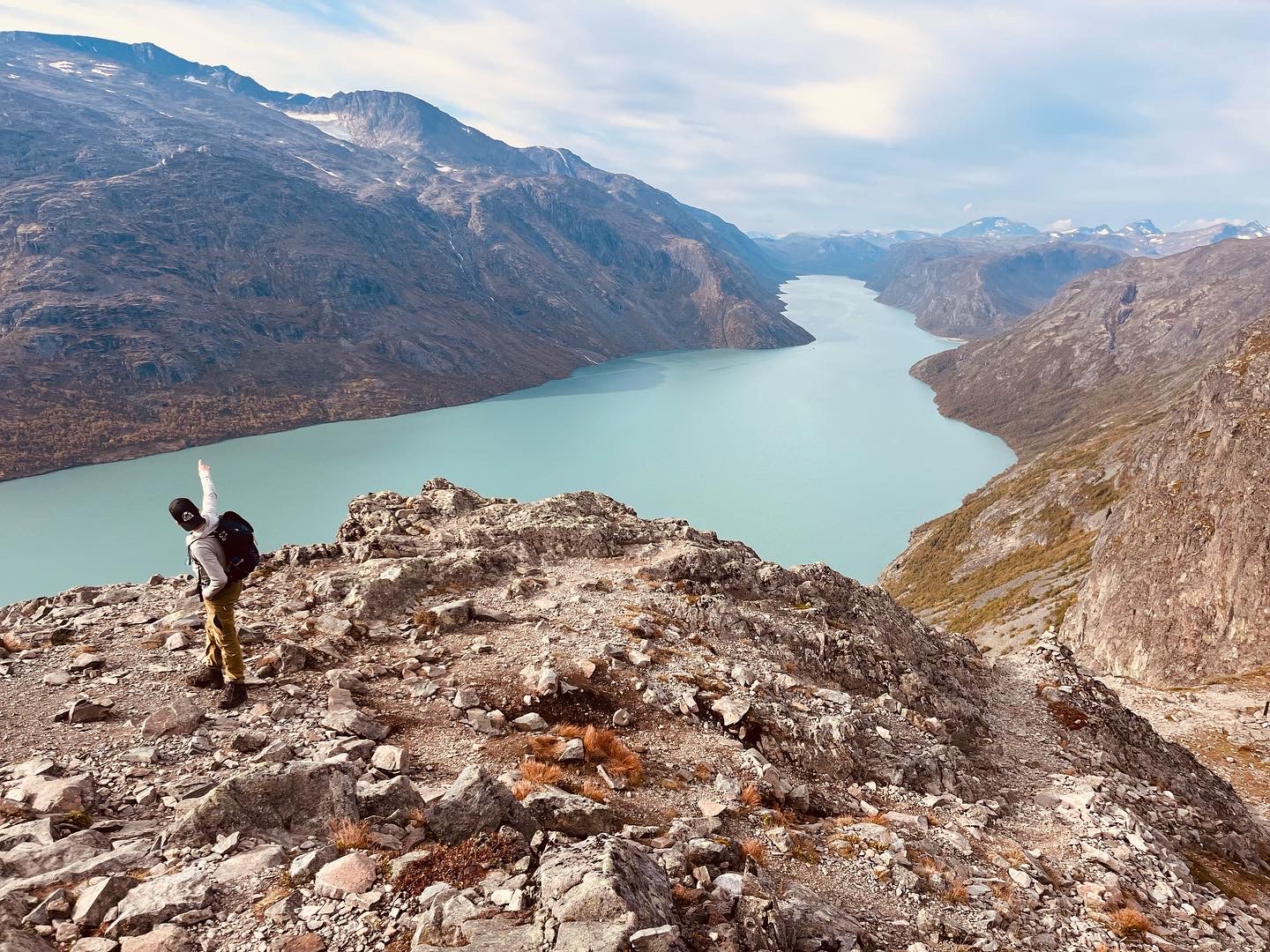 en person som står på en steinete åsside med utsikt over en innsjø